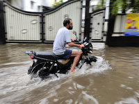 A man is riding a bike in a waterlogged street after heavy rains in Kolkata, India, on August 3, 2024. (