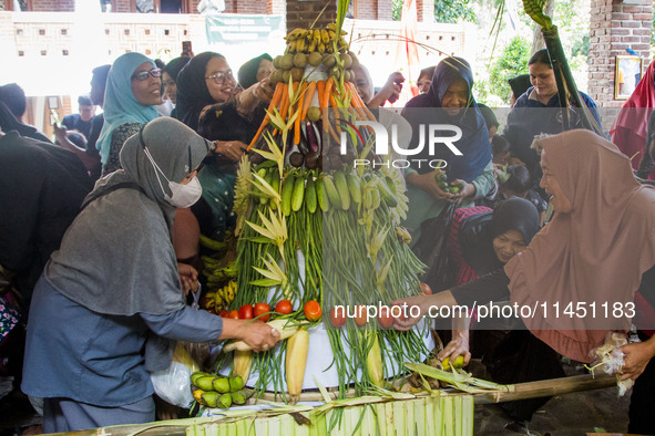 People are jostling the 'Gunungan', a sacrifice in the shape of a mountain, during the Ngemban Taun traditional ceremony in Cireundeu Villag...