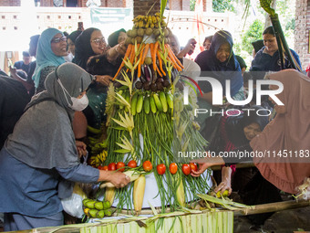 People are jostling the 'Gunungan', a sacrifice in the shape of a mountain, during the Ngemban Taun traditional ceremony in Cireundeu Villag...