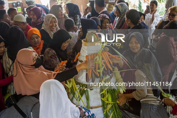 People are jostling the 'Gunungan', a sacrifice in the shape of a mountain, during the Ngemban Taun traditional ceremony in Cireundeu Villag...