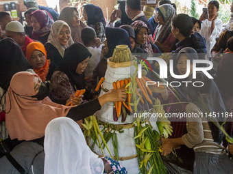 People are jostling the 'Gunungan', a sacrifice in the shape of a mountain, during the Ngemban Taun traditional ceremony in Cireundeu Villag...