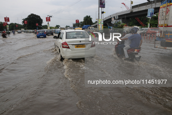 Commuters are wading through the waterlogged busy road during heavy monsoon rain in Kolkata, India, on August 3, 2024. 