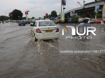 Commuters are wading through the waterlogged busy road during heavy monsoon rain in Kolkata, India, on August 3, 2024. (