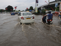 Commuters are wading through the waterlogged busy road during heavy monsoon rain in Kolkata, India, on August 3, 2024. (