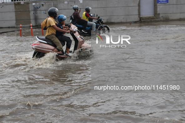 A motorcycle is wading through the waterlogged busy road during the heavy monsoon rain in Kolkata, India, on August 3, 2024. 