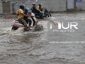 A motorcycle is wading through the waterlogged busy road during the heavy monsoon rain in Kolkata, India, on August 3, 2024. (