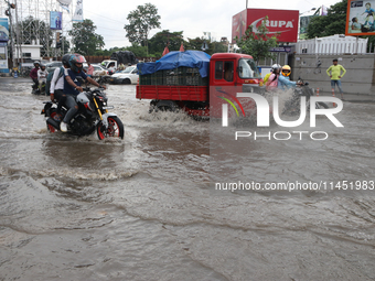 Commuters are wading through the waterlogged busy road during heavy monsoon rain in Kolkata, India, on August 3, 2024. (