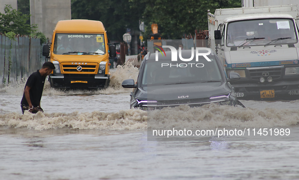 Commuters are wading through the waterlogged busy road during heavy monsoon rain in Kolkata, India, on August 3, 2024. 