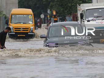 Commuters are wading through the waterlogged busy road during heavy monsoon rain in Kolkata, India, on August 3, 2024. (