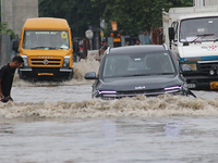 Commuters are wading through the waterlogged busy road during heavy monsoon rain in Kolkata, India, on August 3, 2024. (