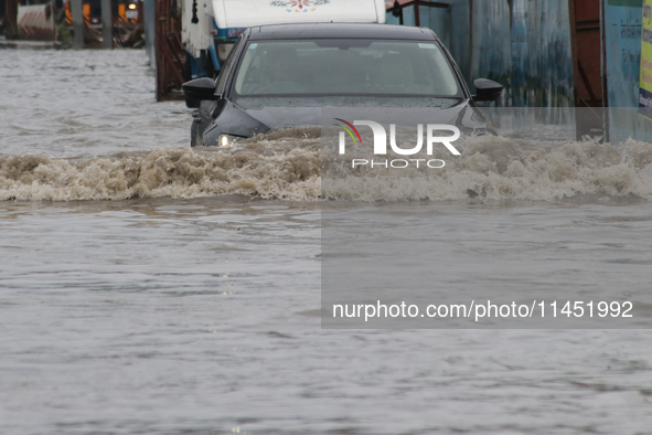 Commuters are wading through the waterlogged busy road during heavy monsoon rain in Kolkata, India, on August 3, 2024. 