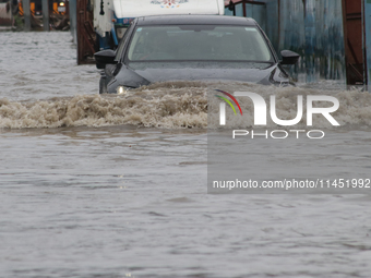 Commuters are wading through the waterlogged busy road during heavy monsoon rain in Kolkata, India, on August 3, 2024. (