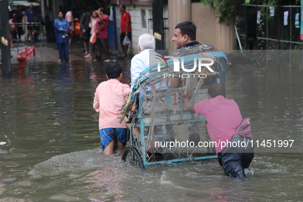 People are wading through a flooded street during the heavy monsoon rain in Kolkata, India, on August 3, 2024. 