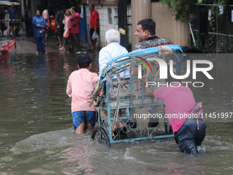 People are wading through a flooded street during the heavy monsoon rain in Kolkata, India, on August 3, 2024. (