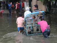 People are wading through a flooded street during the heavy monsoon rain in Kolkata, India, on August 3, 2024. (