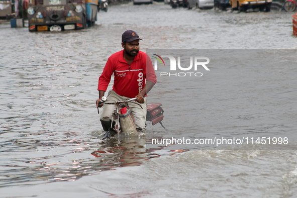 A Zomato food delivery boy is riding his bicycle through the waterlogged busy road during the heavy monsoon rain in Kolkata, India, on Augus...