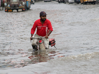 A Zomato food delivery boy is riding his bicycle through the waterlogged busy road during the heavy monsoon rain in Kolkata, India, on Augus...