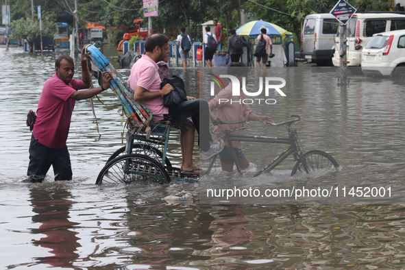 A person is riding a rickshaw with his relative through the waterlogged busy road and going to the nearby hospital during the heavy monsoon...