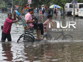 A person is riding a rickshaw with his relative through the waterlogged busy road and going to the nearby hospital during the heavy monsoon...