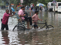 A person is riding a rickshaw with his relative through the waterlogged busy road and going to the nearby hospital during the heavy monsoon...