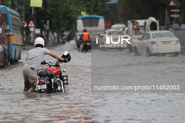 People are wading through a flooded street during the heavy monsoon rain in Kolkata, India, on August 3, 2024. 