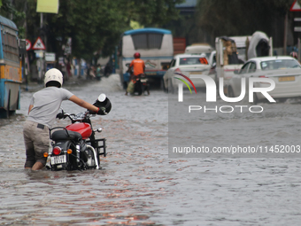 People are wading through a flooded street during the heavy monsoon rain in Kolkata, India, on August 3, 2024. (