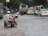 People are wading through a flooded street during the heavy monsoon rain in Kolkata, India, on August 3, 2024. (