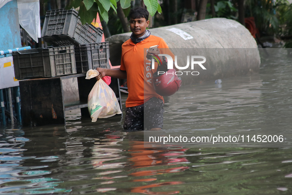 A Swiggy food delivery boy is walking through a flooded street during the heavy monsoon rain in Kolkata, India, on August 3, 2024. 