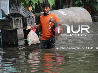 A Swiggy food delivery boy is walking through a flooded street during the heavy monsoon rain in Kolkata, India, on August 3, 2024. (