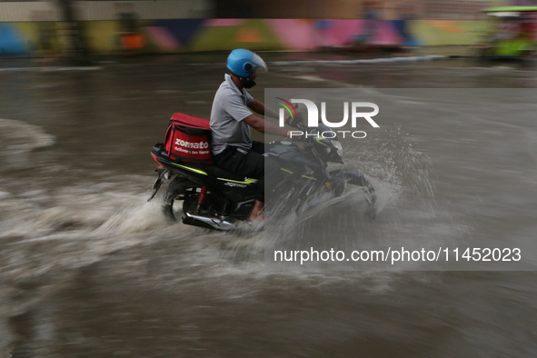 A Zomato delivery person is being seen on a flooded street during the heavy monsoon rain in Kolkata, India, on August 3, 2024. 