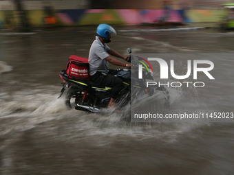 A Zomato delivery person is being seen on a flooded street during the heavy monsoon rain in Kolkata, India, on August 3, 2024. (