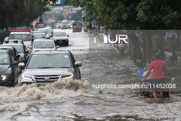 Vehicles are driving through a flooded street during the heavy monsoon rain in Kolkata, India, on August 3, 2024. 