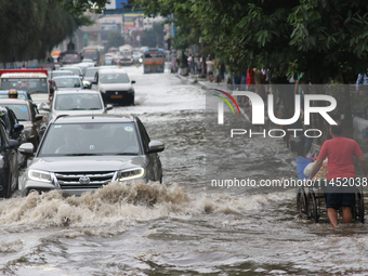 Vehicles are driving through a flooded street during the heavy monsoon rain in Kolkata, India, on August 3, 2024. (