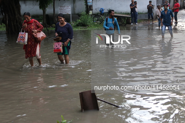 Commuters are wading through the waterlogged busy road during heavy monsoon rain in Kolkata, India, on August 3, 2024. 