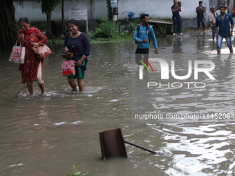 Commuters are wading through the waterlogged busy road during heavy monsoon rain in Kolkata, India, on August 3, 2024. (