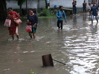 Commuters are wading through the waterlogged busy road during heavy monsoon rain in Kolkata, India, on August 3, 2024. (