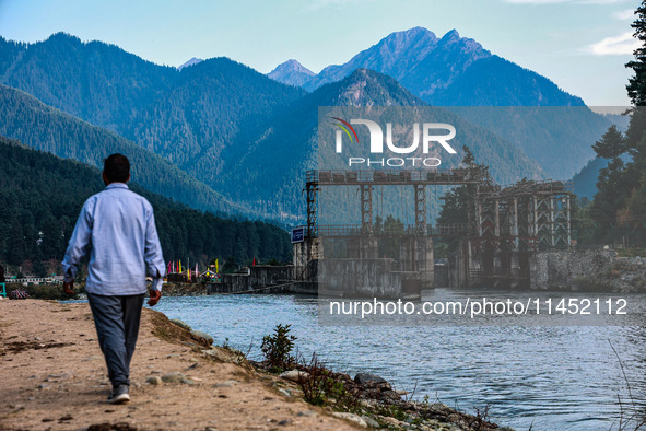 A man is walking as a power project is being seen on the banks of River Lidder in Pahalgam, Jammu and Kashmir, India, on August 3, 2024. 