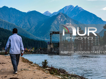 A man is walking as a power project is being seen on the banks of River Lidder in Pahalgam, Jammu and Kashmir, India, on August 3, 2024. (