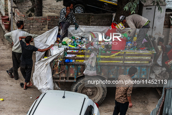 People are unloading garbage-filled dustbins onto a municipal waste collection truck in Pahalgam, Jammu and Kashmir, India, on August 3, 202...