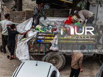 People are unloading garbage-filled dustbins onto a municipal waste collection truck in Pahalgam, Jammu and Kashmir, India, on August 3, 202...