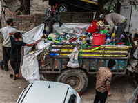 People are unloading garbage-filled dustbins onto a municipal waste collection truck in Pahalgam, Jammu and Kashmir, India, on August 3, 202...