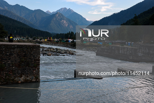 A boy is sitting on a concrete wall on the banks of the river Lidder in Pahalgam, Jammu and Kashmir, India, on August 3, 2024. 