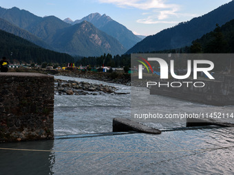 A boy is sitting on a concrete wall on the banks of the river Lidder in Pahalgam, Jammu and Kashmir, India, on August 3, 2024. (