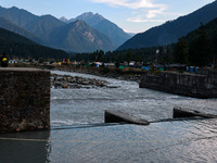 A boy is sitting on a concrete wall on the banks of the river Lidder in Pahalgam, Jammu and Kashmir, India, on August 3, 2024. (