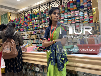 A salesgirl is standing by shelves filled with fabric borders used to make saree blouses at a textile shop in Thiruvananthapuram, Kerala, In...