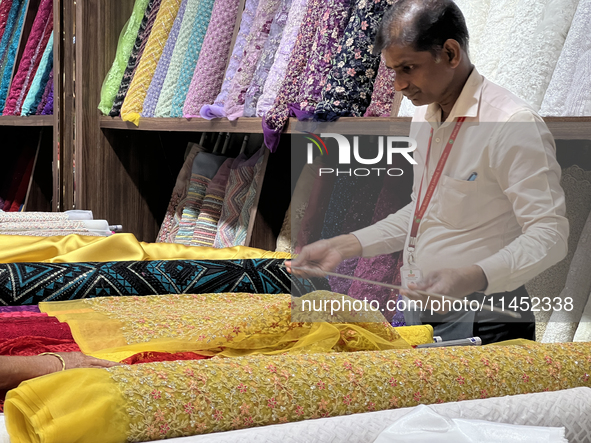 An employee is measuring fabric for a customer at a textile shop in Thiruvananthapuram, Kerala, India, on April 08, 2024. 