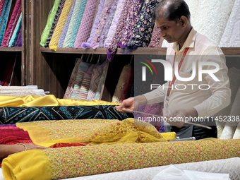 An employee is measuring fabric for a customer at a textile shop in Thiruvananthapuram, Kerala, India, on April 08, 2024. (