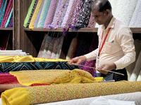 An employee is measuring fabric for a customer at a textile shop in Thiruvananthapuram, Kerala, India, on April 08, 2024. (