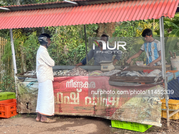 A man is purchasing fish from a roadside stand selling fresh fish and prawns in Adoor, Pathanamthitta, Kerala, India, on April 06, 2024. 