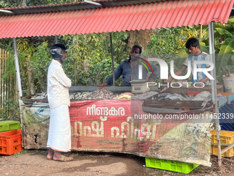 A man is purchasing fish from a roadside stand selling fresh fish and prawns in Adoor, Pathanamthitta, Kerala, India, on April 06, 2024. (